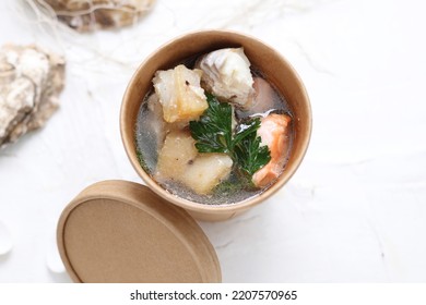 Fish Soup With Salmon And Shrimps. Fish Broth Soup In A Take-away Carton Box, On A White Background, Top View, Selective Focus.