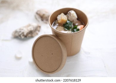 Fish Soup With Salmon And Shrimps. Fish Broth Soup In A Take-away Carton Box, On A White Background, Top View, Selective Focus.