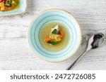 Fish soup with vegetables on white wooden table