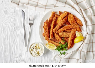 Fish Sticks, Fish Fillet Fingers Breaded And Deep-fried Served On A White Plate On A Wooden Table With Tartar Sauce And Lemon Wedges, Horizontal View From Above, Flat Lay Free Space