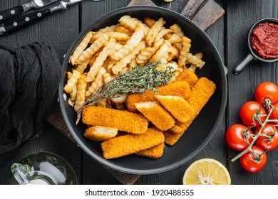 Fish Sticks with vegetables set, on frying iron pan, on black wooden table background, top view flat lay