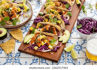 Fish tacos with mango salsa and red cabbage, salmon tacos board with beer and hot honey - Powered by Shutterstock