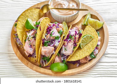 Fish Tacos With Red Cabbage Salad With Spicy Yogurt Sauce Sprinkled With Finely Chopped Parsley Served On A Bamboo Plate On A White Wooden Table, Horizontal View From Above, Close-up