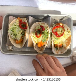 Fish Tacos In Tray On Beach Towel With Girls Hand