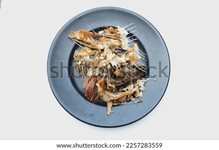 fishbone,Bones or Scrap of food in the black plate after eating. Remains of fried fish. food scraps.
