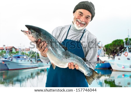 Fisher holding a big atlantic salmon fish in the fishing harbor