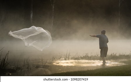 Fisherman Casting Net On Foggy River