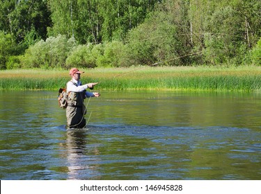 Fisherman catches of chub  fly fishing in the Chusovaya river in the afternoon