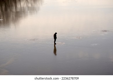 Fisherman catches fish in an ice hole in winter on smooth ice. - Shutterstock ID 2236278709