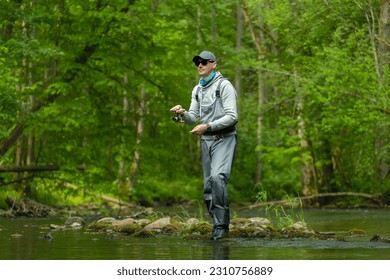 Fisherman catching brown trout on spinning tackle standing in river. - Powered by Shutterstock