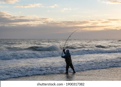 Fisherman fishing at the beach with the waves rolling in at sunrise.