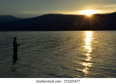 Fisherman Fishing In McDonald Lake In Glacier National Park, Montana At Sunset In Summer