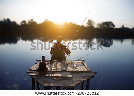 the fisherman is fishing on a lake in the early morning.