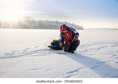 A fisherman is fishing with a winter spinning rod on a frozen lake. Ice fishing concert. - Powered by Shutterstock