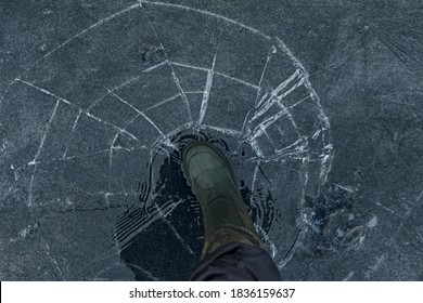 Fisherman Foot On Broken Cracked Thin Ice At Lake. Dangerous Fishing