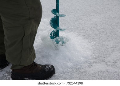 A Fisherman With A Hand Auger Drills A Hole In The Ice