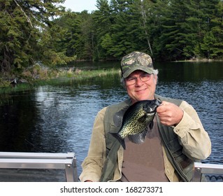fisherman holding a crappie caught on a freshwater lake