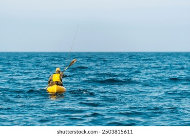 Fisherman kayaker paddling canoe out to sea with oars extended