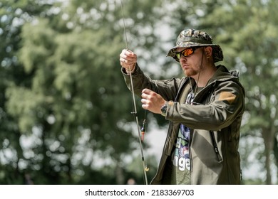 Fisherman On The Water.
Close Up Of A Man, Holding A Fishing Rod. Sunset Soft Light, Selective Focus, Blurred Forest And Lake In The Background. Vacation, Camping, Fishing, Relaxing And Hobby Concept.