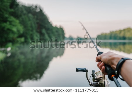 Fishing rod, spinning reel on the background pier river bank