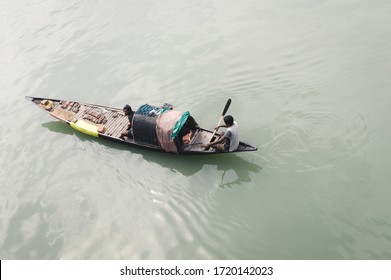 A Fisherman Rowing His Narrow Fishing Boat In The Ganges River. Commercial Fishing Net On His Nautical Vessel. Rural Scene. High Angle View. Fishing Industry Background. Kerala India. March 2020