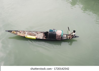 A Fisherman Rowing His Narrow Fishing Boat In The Ganges River. Commercial Fishing Net On His Nautical Vessel. Rural Scene. High Angle View. Fishing Industry Background. Kerala India. March 2020