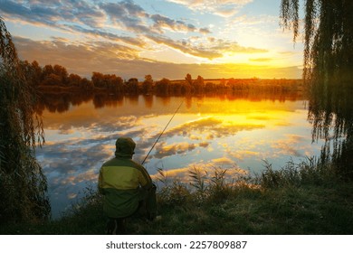 Fisherman seated by the lake at sunset under a dramatic sky - Shutterstock ID 2257809887