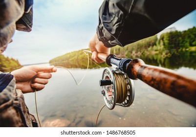 Fisherman spool of rope using rod fly fishing in river.