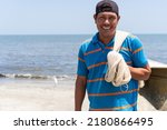 Fisherman standing on beach, smiling, portrait