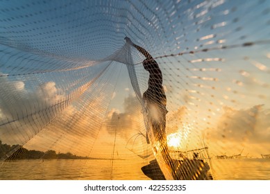 Fisherman throwing fishing net during sunrise in Pak Pra, Phatthalung, Thailand
