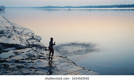 Fisherman throwing net in Datta River at peaceful morning, Pakhiralay town, Sundarban National Park, West Bengal, India