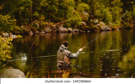 Fisherman using rod fly fishing in mountain river.