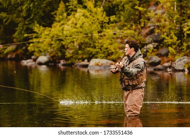 Fisherman Using Rod Fly Fishing In Mountain River Sunset.