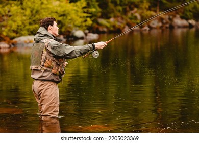 Fisherman Using Rod Fly Fishing In Mountain River Sunset.