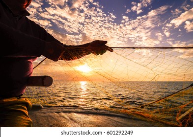 Fisherman's hand silhouette  throwing fishing net at sunset, Crete, Greece - Shutterstock ID 601292249