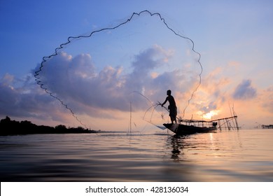 Fishermen on boat fishing with a fishnet,the old traditional equipment of Thai fishery.Silhouette scene in Pak Pra Village, Pattalung province, Thailand.