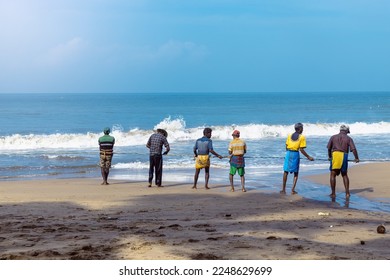 Fishermen pull their nets on the beach.  