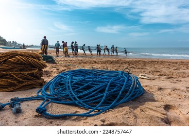 Fishermen pull their nets on the beach.  