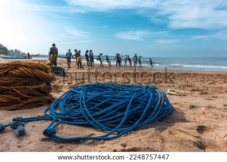 Fishermen pull their nets on the beach.  