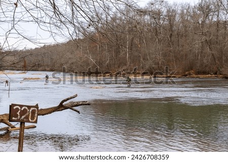 Fishermen wandering along the Chattahoochee River. The river floor becomes shallow and safe to across by just walking as spring approaches. People can simply stroll from this bank to the other bank