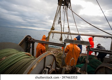 Fishermen in waterproof suits on the deck of the fishing seiner. Morning time.