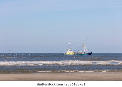 Fishery concept, Fishing boat sailing in the sea with net or trawl on the side to catch the fish, Flying seagulls birds behind eating fishes from fisherman, Dutch north sea, Noord Holland, Netherlands - Powered by Shutterstock