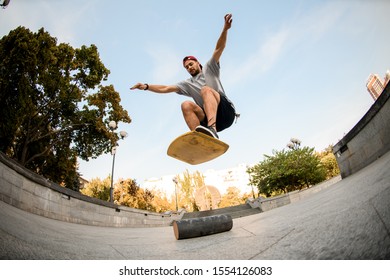 Fish-eye Shot From Below Man Jumping On The Balance Board On The Concrete Border In The Background Of Blue Clear Sky