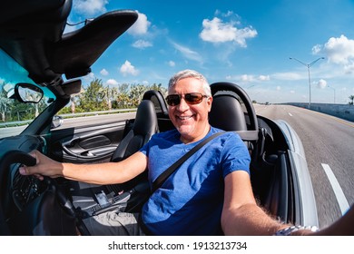 Fisheye View Of A Handsome Middle Age Man Driving A Convertible Automobile On The Highway.