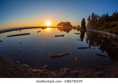 Fisheye wide angle shot of Ruby Beach on the olympic peninsula just before sunset with people on the horizon.
