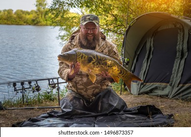 Fishing adventures, carp fishing. Mirror carp (Cyprinus carpio), freshwater fish. Angler with a big carp fishing trophy.Sunrise with a Carp Angler overlooking Lake
