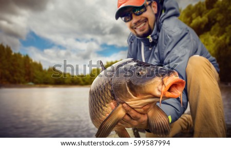 Fishing backgrounds. Young man hold big carp in his hands.