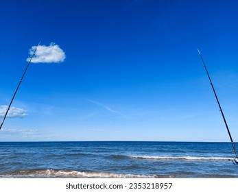 Fishing from the beach with two rods. Relaxing on the beach on a sunny summer day. The sea and blue sky in the background. - Powered by Shutterstock