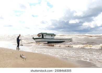 A fishing boat anchored on the beach and a fisherman with his fishing net. - Powered by Shutterstock