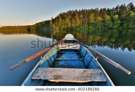 fishing boat in a calm lake water/old wooden fishing boat/ wooden fishing boat in a still lake water